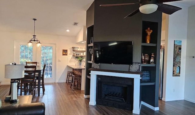 living area featuring built in features, visible vents, a fireplace, and wood finished floors