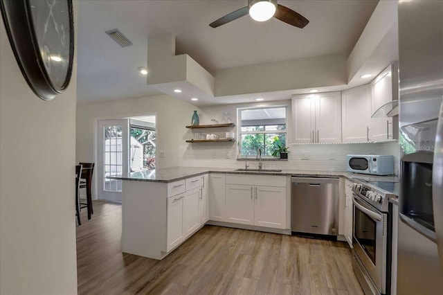 kitchen with stone countertops, white cabinets, a sink, stainless steel appliances, and backsplash