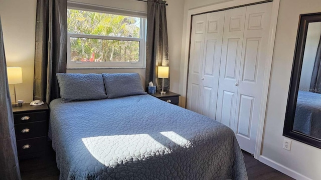 bedroom with dark wood-style flooring, a closet, and baseboards