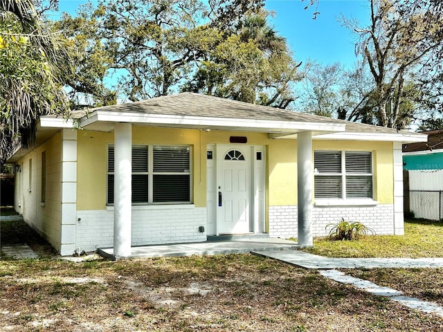 bungalow-style house featuring a shingled roof, fence, and brick siding