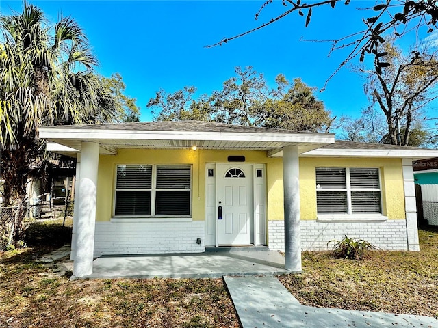 bungalow-style house with brick siding, fence, and stucco siding