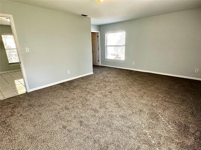 tiled empty room with carpet floors, visible vents, and baseboards