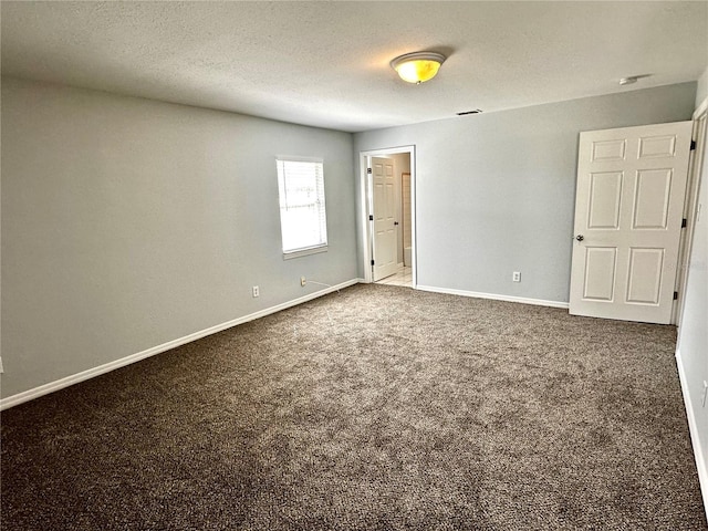 carpeted spare room with a textured ceiling and baseboards