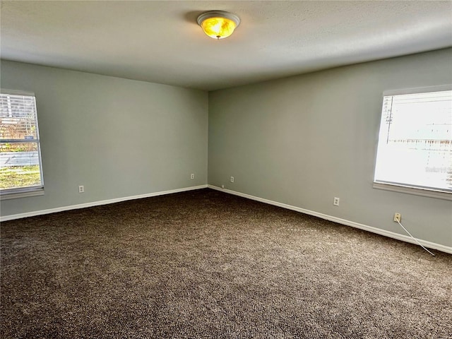 unfurnished room featuring baseboards and dark carpet