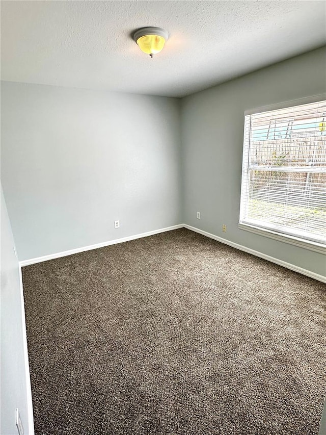 unfurnished room featuring dark carpet, a textured ceiling, and baseboards