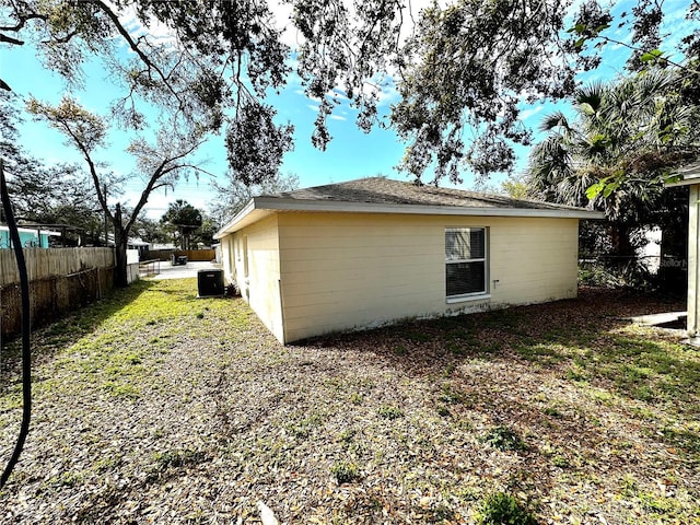 view of side of home with central AC unit and fence