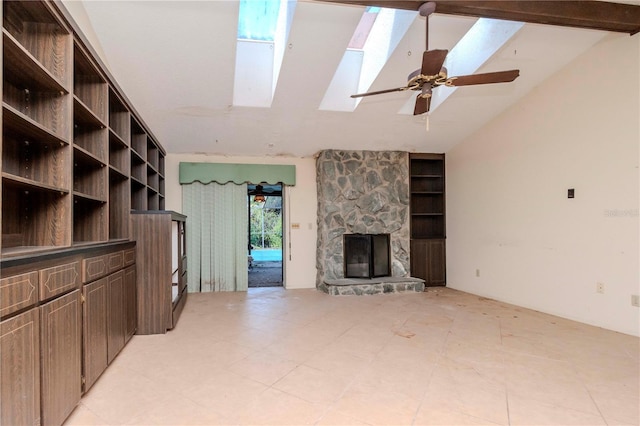 unfurnished living room with ceiling fan, vaulted ceiling with skylight, and a fireplace