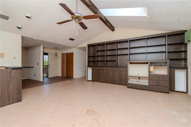 unfurnished living room with visible vents, ceiling fan, lofted ceiling with beams, and a textured ceiling