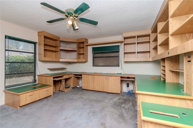 interior space with ceiling fan, open shelves, a textured ceiling, and built in study area