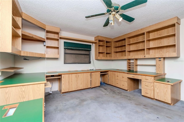 unfurnished office with built in study area, unfinished concrete flooring, a textured ceiling, and ceiling fan