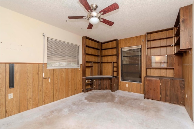 empty room featuring a textured ceiling, a wainscoted wall, and wooden walls