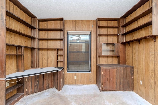 interior space featuring wood walls, unfinished concrete floors, and a textured ceiling