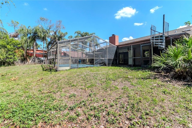 view of yard featuring glass enclosure and a ceiling fan