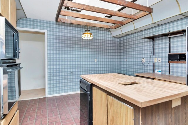 5101 Estates Cir, Sarasota, FL 34243 - kitchen with wood counters, black oven, wallpapered walls, brick patterned flooring, and light brown cabinetry