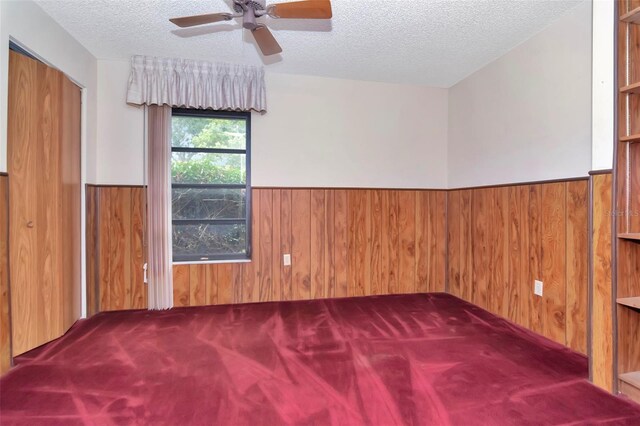 5101 Estates Cir, Sarasota, FL 34243 - carpeted spare room featuring wood walls, a wainscoted wall, a ceiling fan, and a textured ceiling
