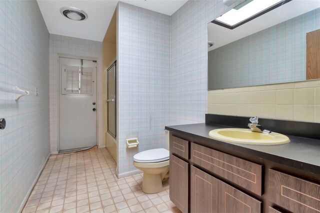 5101 Estates Cir, Sarasota, FL 34243 - full bath featuring tile walls, vanity, bath / shower combo with glass door, and tile patterned floors