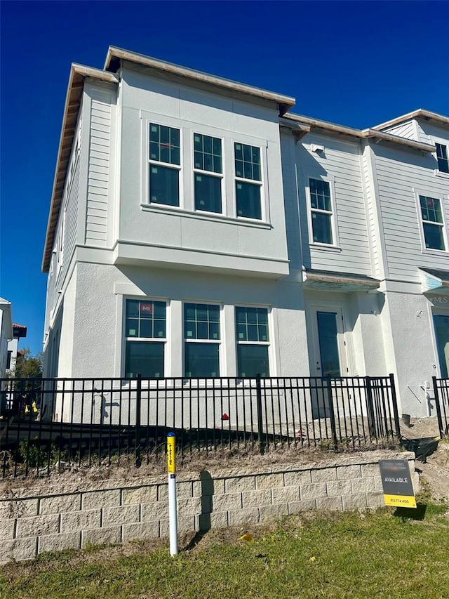 view of front facade with fence and stucco siding