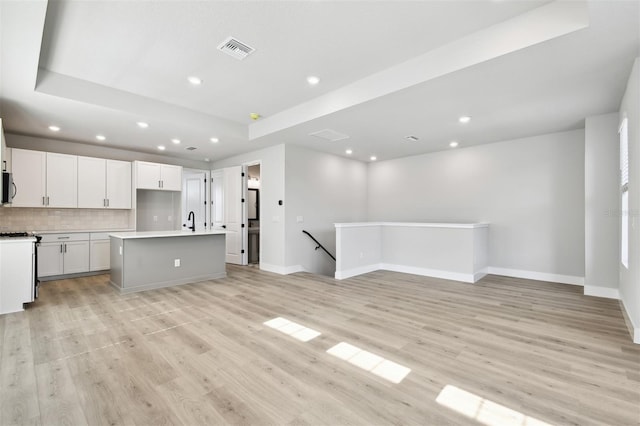 4717 W Mccoy St Unit 9, Tampa, FL 33616 - kitchen with open floor plan, recessed lighting, stainless steel microwave, a center island with sink, and light wood-style flooring