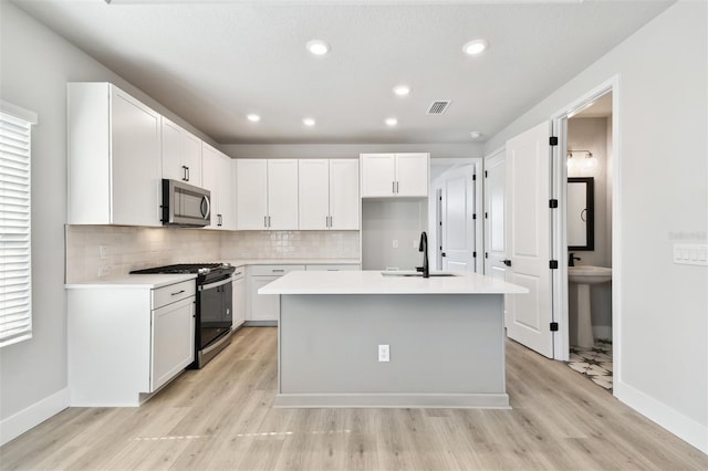 4717 W Mccoy St Unit 9, Tampa, FL 33616 - kitchen with gas range oven, a sink, stainless steel microwave, light wood-style flooring, and baseboards