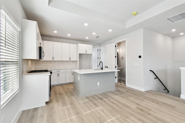 4717 W Mccoy St Unit 9, Tampa, FL 33616 - kitchen featuring stainless steel microwave, a sink, light wood-style flooring, decorative backsplash, and recessed lighting