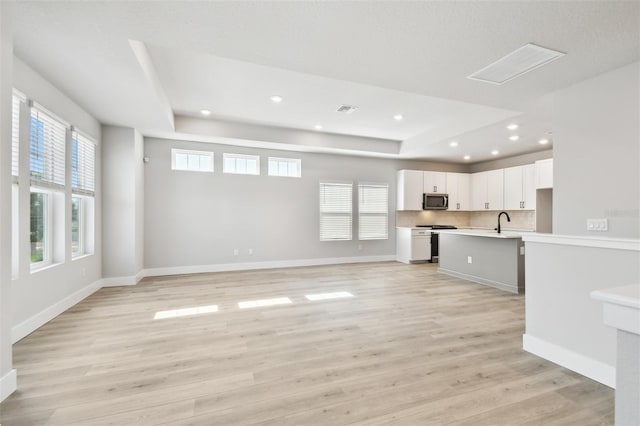 4717 W Mccoy St Unit 9, Tampa, FL 33616 - unfurnished living room with a tray ceiling, light wood-style floors, recessed lighting, a sink, and baseboards