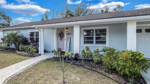 view of front of home featuring a shingled roof, a front yard, and stucco siding