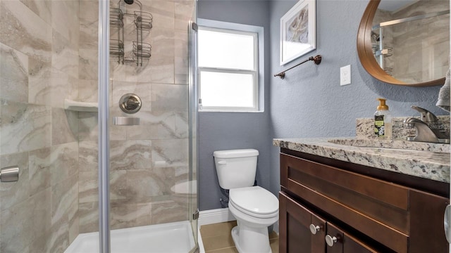 bathroom featuring a textured wall, toilet, vanity, baseboards, and a stall shower