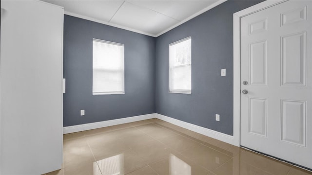 empty room featuring tile patterned flooring, baseboards, and crown molding