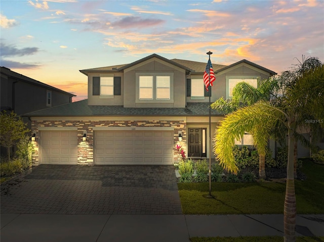 view of front of property with stone siding, decorative driveway, and stucco siding