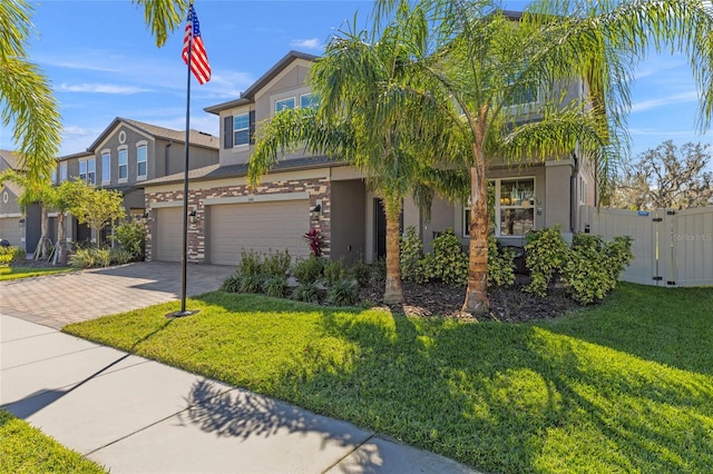 view of front of property featuring a garage, a gate, decorative driveway, a front lawn, and stucco siding