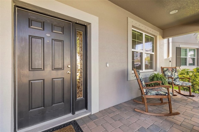 doorway to property with a porch and stucco siding