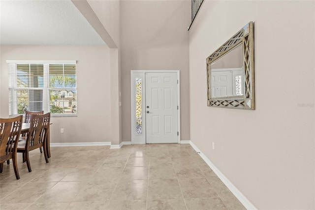 foyer featuring a high ceiling, light tile patterned flooring, and baseboards