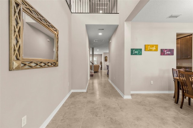 corridor with light tile patterned flooring, visible vents, and baseboards