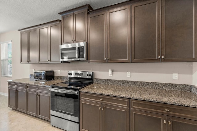 kitchen with a toaster, appliances with stainless steel finishes, dark stone counters, and dark brown cabinets