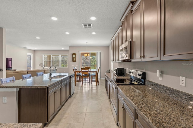 kitchen featuring a center island with sink, stainless steel appliances, visible vents, light tile patterned flooring, and a sink