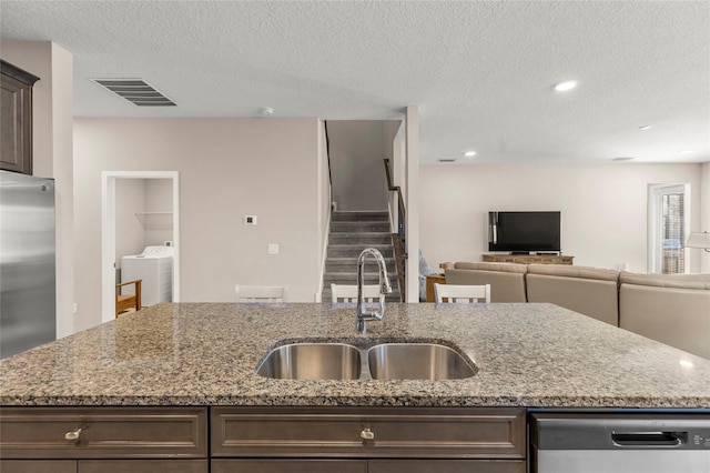 kitchen featuring appliances with stainless steel finishes, a sink, visible vents, and dark brown cabinetry