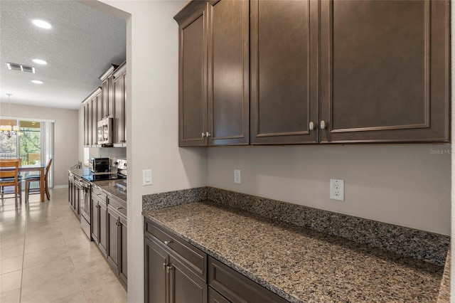 kitchen with stainless steel appliances, visible vents, a textured ceiling, and dark brown cabinets