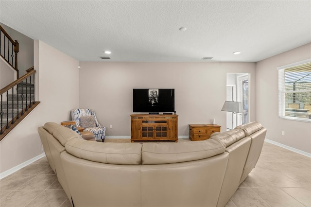 living room featuring stairs, a textured ceiling, visible vents, and baseboards