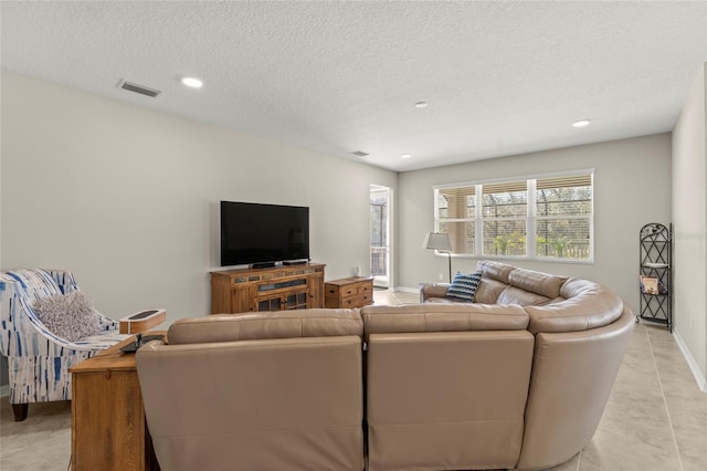 living area with light tile patterned floors, recessed lighting, visible vents, a textured ceiling, and baseboards