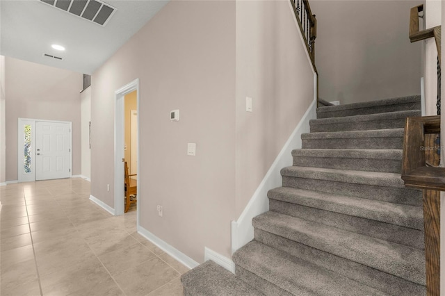 staircase featuring tile patterned flooring, visible vents, and baseboards