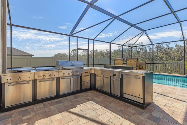 view of patio featuring glass enclosure, an outdoor kitchen, fence, and a fenced in pool