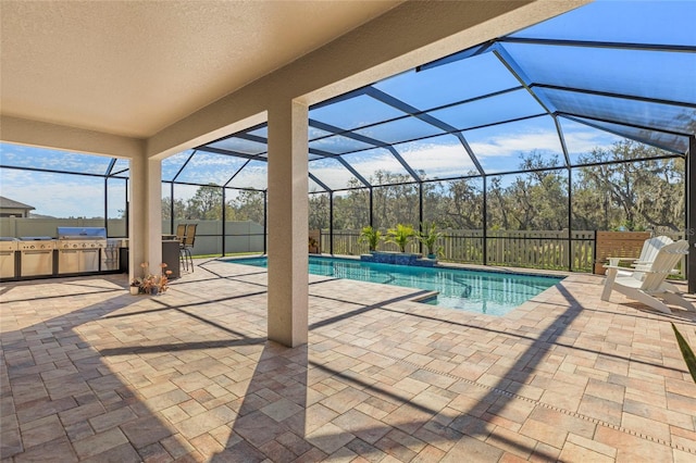 view of pool featuring glass enclosure, an outdoor kitchen, a fenced backyard, a fenced in pool, and a patio area