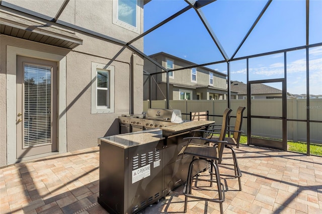 view of patio with glass enclosure, fence, outdoor dry bar, and area for grilling