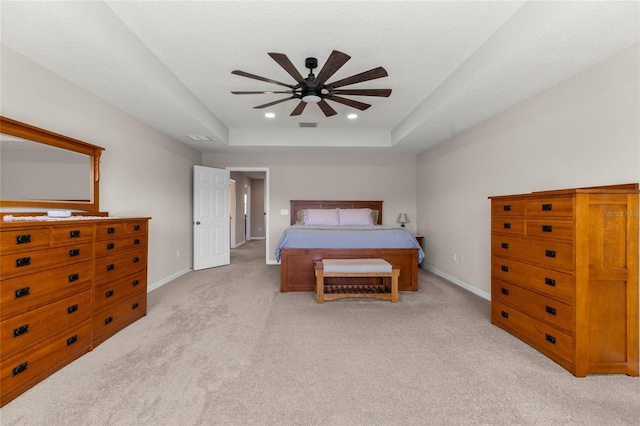 carpeted bedroom with a tray ceiling, recessed lighting, visible vents, a ceiling fan, and baseboards