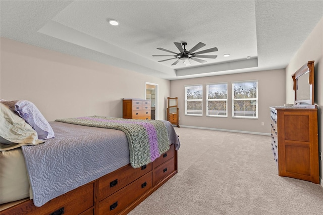 bedroom featuring a textured ceiling, baseboards, a raised ceiling, and light colored carpet