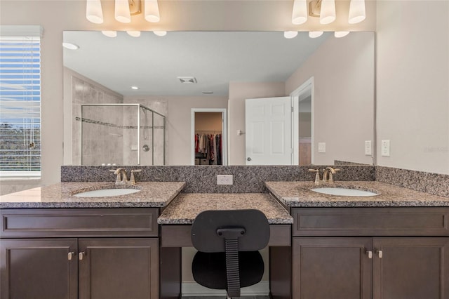 bathroom featuring a walk in closet, visible vents, a sink, and a shower stall