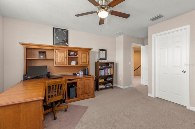 office space with a textured ceiling, light carpet, a ceiling fan, visible vents, and baseboards