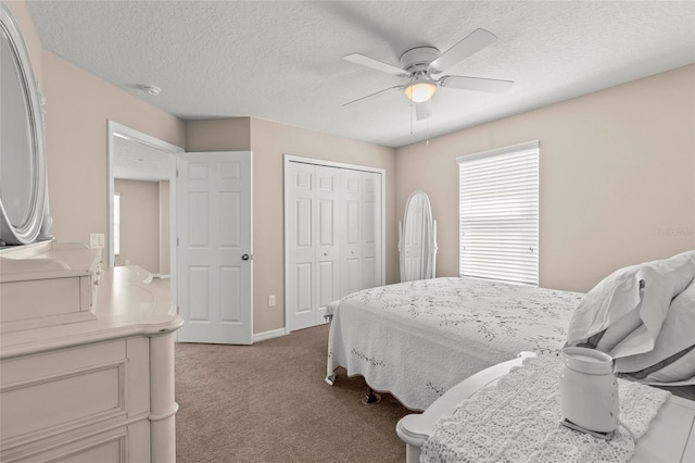 bedroom with baseboards, a ceiling fan, a textured ceiling, carpet floors, and a closet