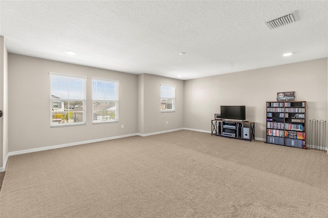 living room with a textured ceiling, carpet floors, visible vents, and baseboards