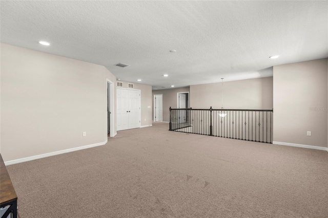 spare room with a textured ceiling, visible vents, and baseboards